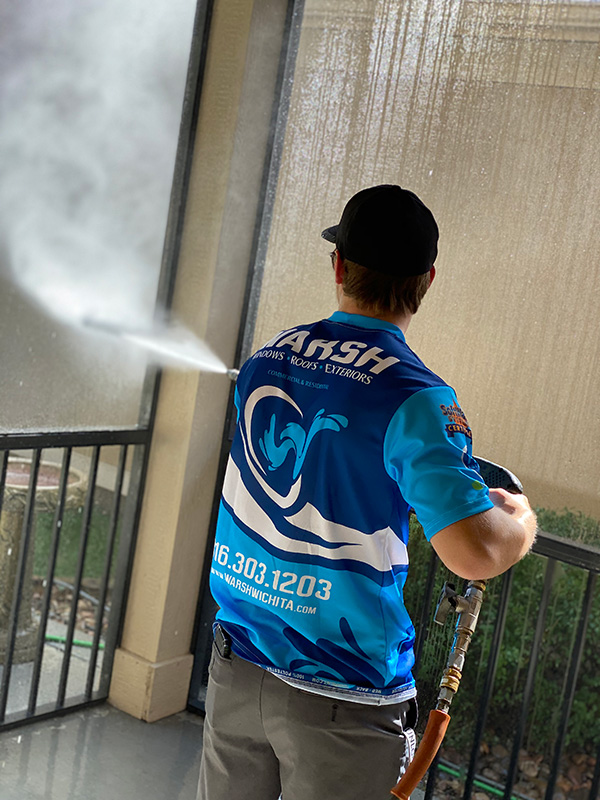 A man in blue shirt washing a window.